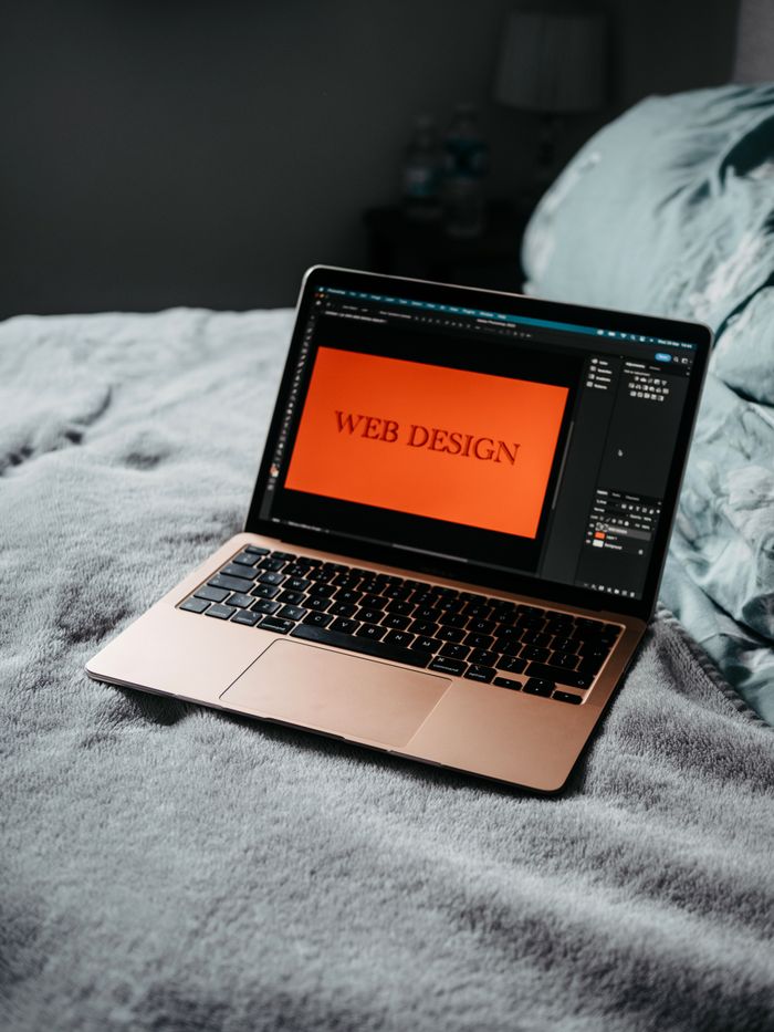 creative-01 A laptop on a bed showing web design software, creating a cozy workspace.